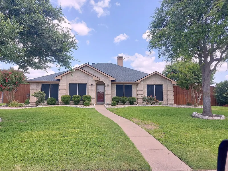 A single-story brick home with a gray shingle roof and a long front walk